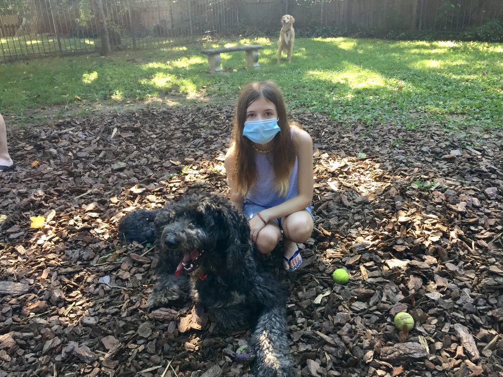 A girl wearing a mask and posing with a dog